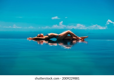 快乐的女孩在夏日海滩度假时玩得开心。年轻女子在山顶无边泳池边放松，欣赏海景。健康的家庭生活方式，带孩子在热带岛屿上度过夏日。