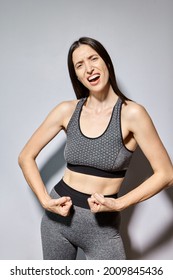 Een vrouw in sportkleding pronkt met haar spieren en lacht
