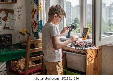 窓と街を背景にラジコンカーを修理する少年