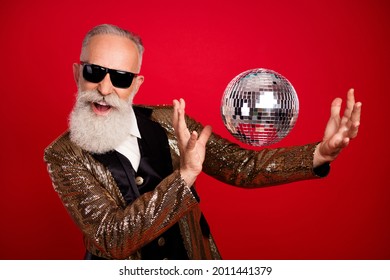 Portrait d'un homme aux cheveux gris attrayant, joyeux et classe, dansant avec un ballon de club isolé sur fond de couleur rouge vif