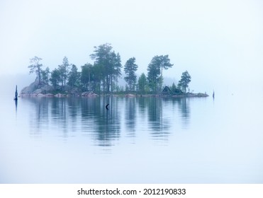 Bosque verde de Islandia en la niebla lechosa profunda. Agua tranquila de un lago en verano. Calma total en un lago brumoso. Una isla disuelta en la niebla en medio de un estanque. Naturaleza escandinava. Viajes a Karelia del Norte