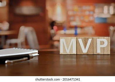 En un tablero de madera blanco dañado, los cubos de palabras de madera están dispuestos en las letras MVP. Es una abreviatura de Producto Mínimo Viable.