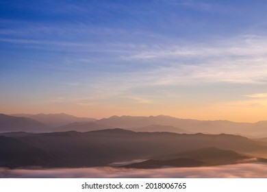 日の出時の霧の海の風景。雲のある美しい青空。シルエットの山。