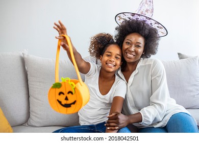 Happy halloween! A mother and her daughter carving pumpkin. Happy family preparing for Halloween. Cheerful young mother and girl are celebrating Halloween