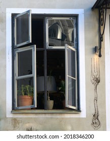 offenes Fenster, Blumen und eine Stehlampe im Inneren. Foto in hoher Qualität