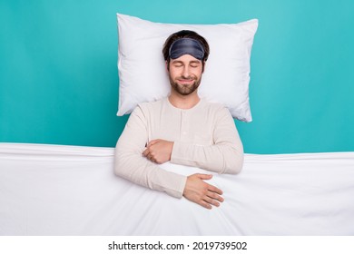 Oben über dem Hochwinkelfoto eines jungen Mannes, der glücklich und positiv lächelt, Bettschlafdecke, Decke, Pyjama, isoliert über blaugrünem Hintergrund