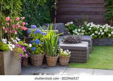 Moderne loungebank in de tuin met bloeiende bloemen, buitenterras in het groene kleurrijke tuinlandschap