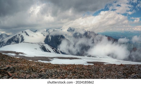 Schneesturm auf der Spitze eines Berges. Wunderbare dramatische Landschaft mit großen schneebedeckten Berggipfeln über niedrigen Wolken. Atmosphärische große Schneeberggipfel im bewölkten Himmel.