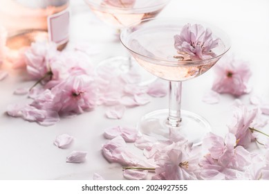 Bodegón romántico con vino rosado en las dos raras copas de champán con hermosas flores suaves, enfoque selectivo. Concepto de bebida rosa, colores pastel