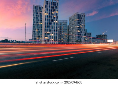 黄昏的城市街道。傍晚的高速公路上，行驶的车辆留下一道道灯光，对面是一群现代建筑。