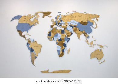 Bản đồ thế giới nhiều lớp màu bằng gỗ trên một bức tường trắng.