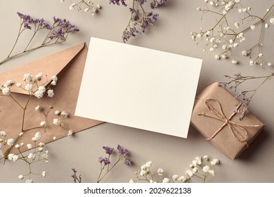 Mockup undangan atau kartu ucapan dengan kotak hadiah dan ranting bunga kering, mockup tampilan atas bergaya dengan ruang fotokopi