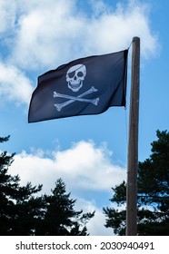 青い空に風になびく黒い海賊の頭蓋骨の旗。海賊行為とハッキングの象徴。