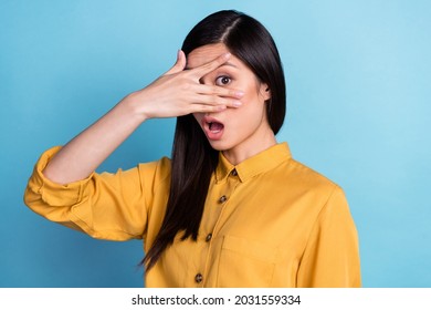 Foto gadis muda Asia yang terkejut, takut, tangan menutupi wajah, mata, pandangan terisolasi di atas latar belakang warna biru