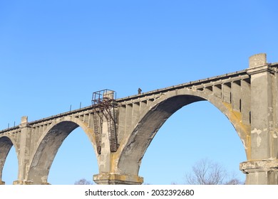 gewölbter Brückenviadukt auf dem Hintergrund einer Winterlandschaft und eines Touristen auf der Brücke