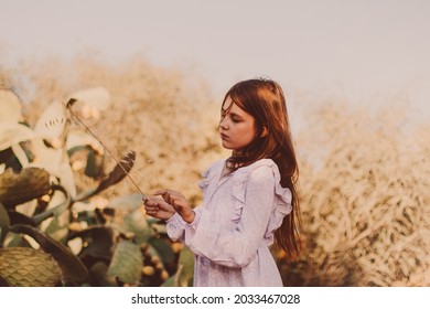 Thoughtful preteen girl wearing eco style boho dress and walking alone in summer field. Teen girl with long brown hairs. Mental health, unity with nature. 