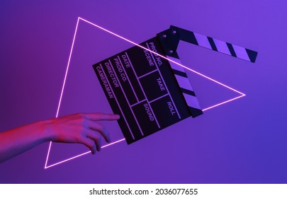 Hand raakt filmklapperbord in neonlicht met driehoek. Bioscoopindustrie, amusement. Concept art, minimalisme