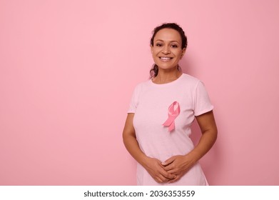 国際乳がんデーを象徴するピンクのサテンのリボンが付いたピンクの T シャツを着た笑顔の混血の女性が、乳がん患者とサバイバーへの連帯と支援を表明しています。10月1日