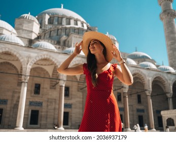 Ein wunderschönes Reiseblogger-Mädchen in einem langen roten Kleid und einem Strohhut wird an den antiken Sehenswürdigkeiten in Istanbul in der Türkei fotografiert. Die Blaue Moschee von Suleiman im Sommer.
