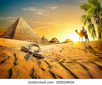 Bedouin on camel near pyramids and ankh in desert