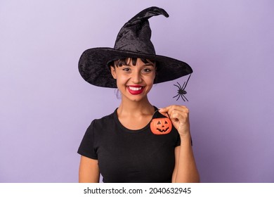 Young mixed race woman disguised as a witch isolated on purple background  happy, smiling and cheerful.