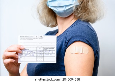 Một phụ nữ trẻ đã được tiêm phòng trong khẩu trang có ghi Phiếu Ghi Tiêm Phòng COVID-19, người khỏe mạnh có giấy ủy nhiệm và được dán trên cánh tay sau khi chủng ngừa vi rút corona. Bằng chứng, con người và khái niệm tiêm vắc-xin.
