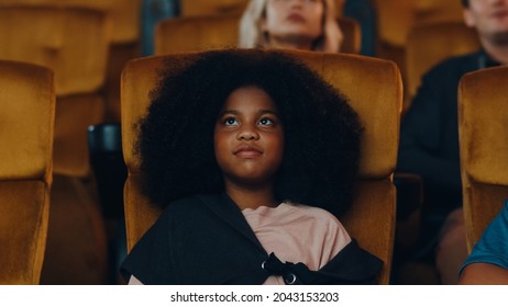 Attractive cheerful young black african girl laughing while watching film in movie theater. Lifestyle entertainment concept.