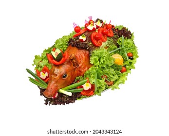 Gebratenes Ferkel dekoriert mit Gemüse auf Platte isoliert auf weißem Hintergrund