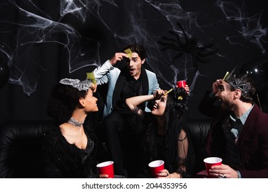 惊讶的男人和穿着万圣节服装的黑人跨种族朋友玩猜猜谁的游戏