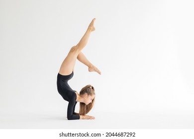 Chica adolescente artística delgada en trenes leotardo negro sobre fondo blanco en ejercicio de gimnasia rítmica, deportes profesionales para niños