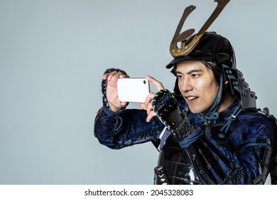 Samurai japonês armado que tira uma foto com um smartphone.