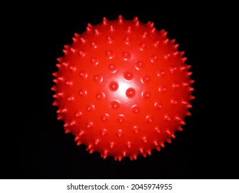 red spiked rubber ball black background.