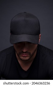 ブランディング アプリケーションのスタジオ写真ですべての黒い帽子をかぶった男。ロゴモックアップ用のフルブラックキャップ