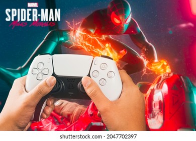 Female hand holding a Playstation 5 Dual Sense Controller with Marvel Spider-Man: Miles Morales game blurred in the background. Rio de Janeiro, RJ, Brazil. September 2021.
