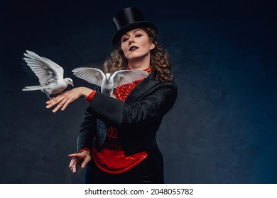 Divertida actriz posando con dos palomas blancas en fondo oscuro
