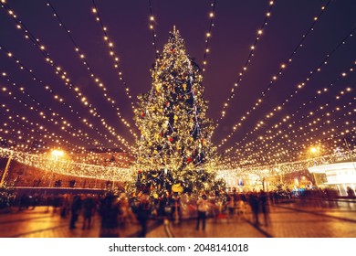 Pohon Natal dan lampu di malam hari di Kyiv. Orang-orang dalam gerakan kabur