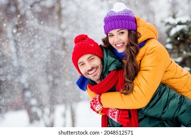 Foto de una encantadora y bonita pareja de matrimonio que usa rompevientos abrazándose sonriendo pasándoselo bien caminando con nieve fuera del parque