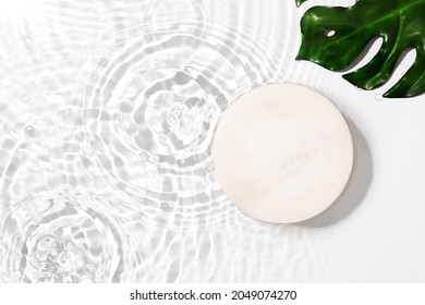 Transparent and clean white water and green leaf background with podium sunlight reflection, top view, beauty backdrop, mock up,