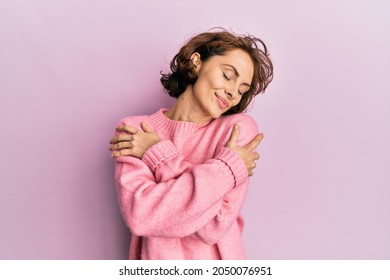 Young brunette woman wearing casual winter sweater hugging oneself happy and positive, smiling confident. self love and self care