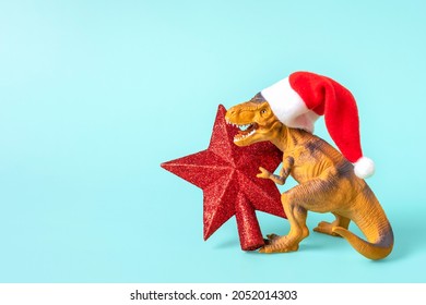 Dinosaure Rex amb barret vermell de Pare Noel té una estrella a les seves potes sobre fons blau Targeta de vacances d'Art de Cap d'Any o Nit de Nadal Idea creativa per al concepte de Bon Nadal