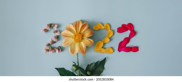 2022-Nummer aus frischen Pflanzen, Blumen und Blättern. Frohes neues Konzept auf blauem Hintergrund. 2022 kreativer Hintergrund, Kartendesign