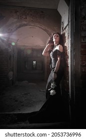 Cô gái Brunette với mái tóc dài trong chiếc váy dạ hội trong lâu đài Gothic cổ điển. Một người phụ nữ trông giống như một phù thủy độc ác hoặc phù thủy trong một nhà thờ cũ bị bỏ hoang. Người mẫu nữ tạo dáng trong Halloween