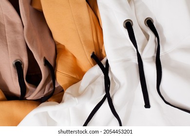 Draufsicht auf den Oversize-Hoodie in Weiß, Beige und Orange. Layout, Draufsicht. Hardware-Details aus nächster Nähe. Mode- und Tragekonzept. Warme, übergroße Kleidung in verschiedenen Farben. Mock-up