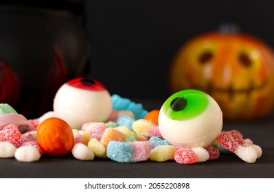 Scary orange pumpkin with delicious and colorful candies, to celebrate Halloween, with a black background, selective focus, concepts, closeup.