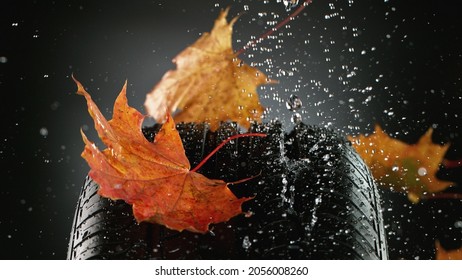 Autoband met vallende herfstbladeren en opspattend water, macrofoto, weerconcept. Studiofoto, vrije ruimte voor tekst.