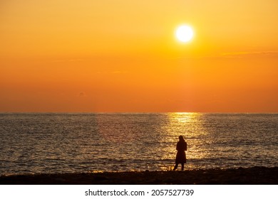 puesta de sol naranja en el mar con un sol brillante. la silueta de un hombre contra el fondo de un camino soleado y brillante. reflejo en la orilla del mar durante la puesta de sol