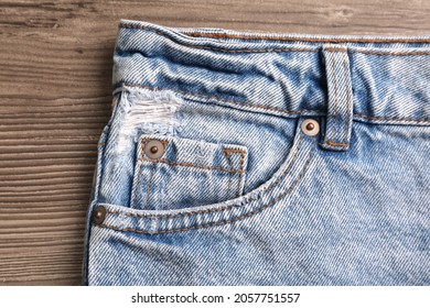 Elegantes jeans azul claro sobre fondo de madera, primer plano del bolsillo insertado