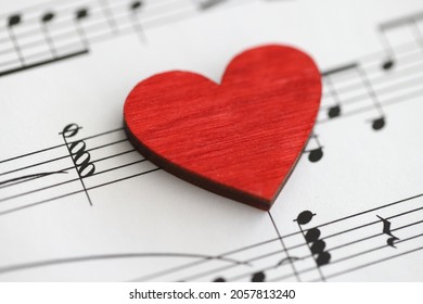 Pequeño corazón rojo de madera con notas musicales de cerca