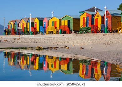 Helder geverfde houtbadhutte by St James Beach, naby Kaapstad, Suid-Afrika.