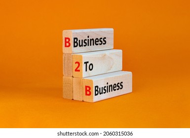 B2B business symbol. Concept words 'BBC - business to business' on wooden blocks on a beautiful orange table, orange background. Business and B2B concept. Copy space.